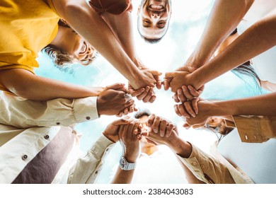 Multi ethnic group of young people holding hands outdoors - Community life style concept with guys and girls hugging together outside - Unity, support and collaboration concept