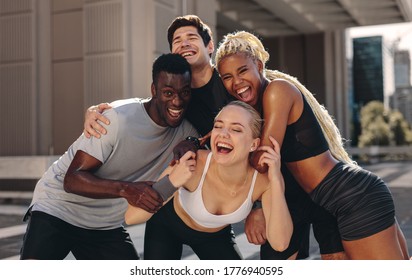 Multi ethnic group of young women exercise outdoor in the city. Men and women in sport clothing standing together and laughing. - Powered by Shutterstock