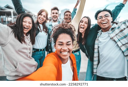 Multi ethnic guys and girls taking selfie pic outdoors with smart mobile phone device - Multiracial community of young people smiling together at camera - Life style concept with teenagers hanging out