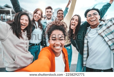 Multi ethnic guys and girls taking selfie pic outdoors with smart mobile phone device - Multiracial community of young people smiling together at camera - Life style concept with teenagers hanging out