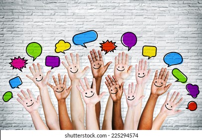 Multi Ethnic People's Hands Raised With Speech Bubble By Brick Wall.