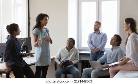 Multi ethnic staff listens attentively to African business coach or trainer, team leader gathered together in modern co-working space. Morning briefing event, business strategies development concept - Shutterstock ID 2191449503