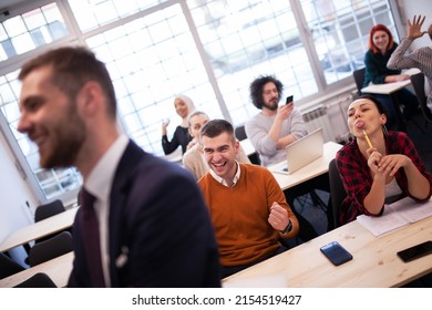 Multi Ethnic Students Making Fun Of Lecturer In A Classroom Behind His Back. Smart Young People Study At A College.