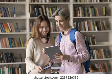 Multi ethnic students standing in classroom use digital tablet, Asian guy show new application, educational website, discuss joint on-line project met in library. Teamwork, study, modern wireless tech - Powered by Shutterstock