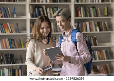 Multi ethnic students standing in classroom use digital tablet, Asian guy show new application, educational website, discuss joint on-line project met in library. Teamwork, study, modern wireless tech