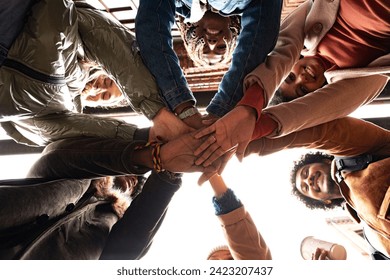 Multi ethnic team stacking hands, smiling, having fun. Photo from below. 