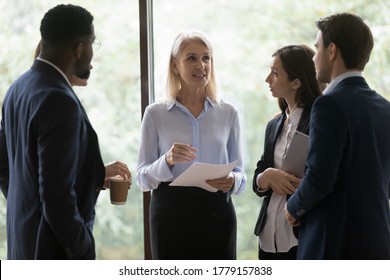Multi ethnic young office employees young professionals staff members surround middle-aged boss female leader ask questions listen guidance feels focused and interested. Mentoring, leadership concept - Shutterstock ID 1779157838