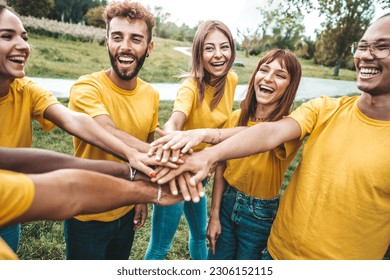 Multi ethnic young people team stacking hands together outside - International university students support and help each other - Friendship, team building, human relationship and diversity concept - Powered by Shutterstock