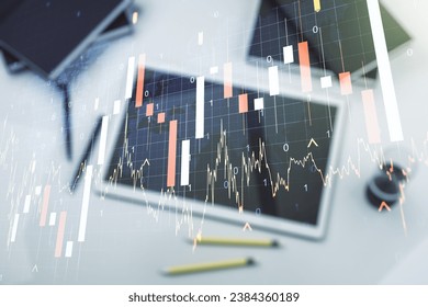 Multi exposure of abstract financial graph with world map and modern digital tablet on desktop on background, top view, financial and trading concept