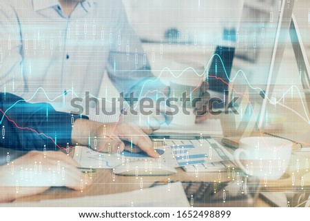 Multi exposure of chart with man typing on computer in office on background. Concept of hard work.