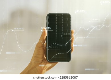 Multi exposure of creative statistics data hologram and hand with cell phone on background, stats and analytics concept