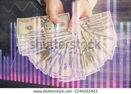 Multi exposure of financial graph drawing hologram and USA dollars bills and man hands. Analysis concept.