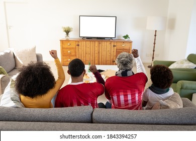 Multi Generation African American Family At Home Sitting On Sofa In Living Room, Watching Sports On TV Cheering. Family Spending Quality Time At Home Together In Slow Motion.