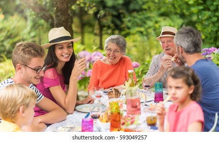 Multi generation family gathered to lunch in the garden in summer, they having fun sitting around a picnic table - Powered by Shutterstock