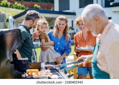 Multi Generation Family Grilling Outside On Backyard In Summer During Garden Party