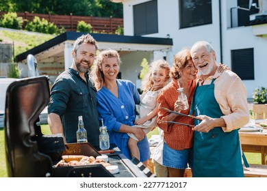 Multi generation family grilling outside on backyard in summer during garden party - Shutterstock ID 2277712017
