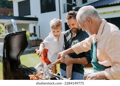 Multi generation family grilling outside on backyard in summer during garden party - Shutterstock ID 2284149775