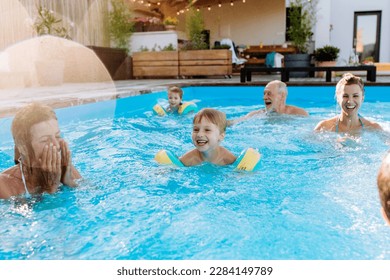 Multi generation family having fun and enjoying swimming in backyard pool during summer holiday. - Shutterstock ID 2284149789