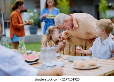 Multi generation family having garden party celebration, grandfather is entertaining grandchildren, laughing and having fun. - Powered by Shutterstock