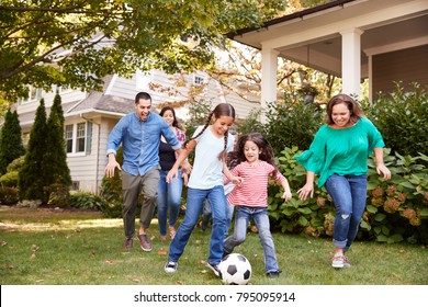 Multi Generation Family Playing Soccer In Garden