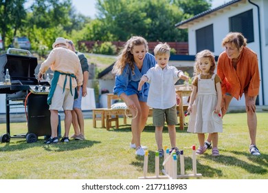 Multi Generation Family Playing Throw A Ring Game When Grilling Outside On Backyard In Summer At Garden Party.