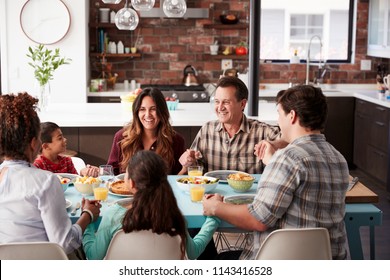 Multi Generation Family Praying Before Meal Around Table At Home