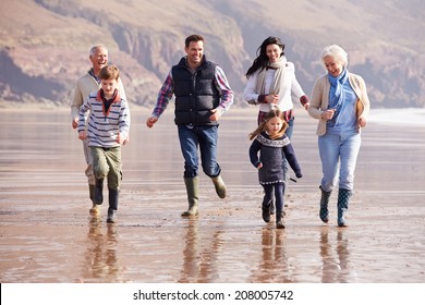 Multi Generation Family Running On Winter Beach