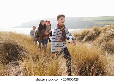 Multi Generation Family In Sand Dunes On Winter Beach