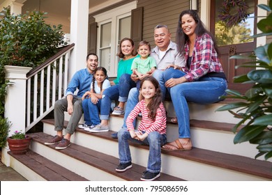 Multi Generation Family Sit On Steps Leading Up To House Porch