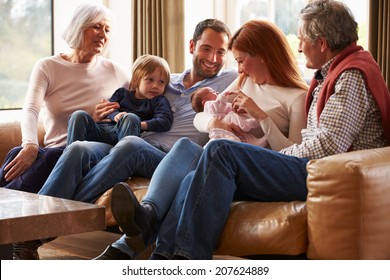 Multi Generation Family Sitting On Sofa With Newborn Baby