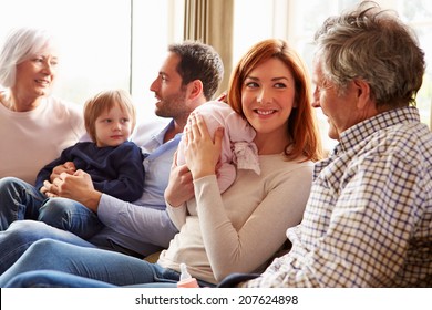 Multi Generation Family Sitting On Sofa With Newborn Baby