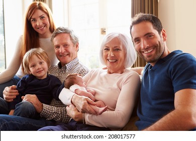 Multi Generation Family Sitting On Sofa With Newborn Baby