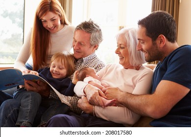 Multi Generation Family Sitting On Sofa With Newborn Baby