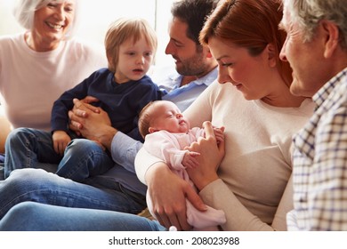 Multi Generation Family Sitting On Sofa With Newborn Baby