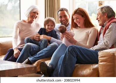 Multi Generation Family Sitting On Sofa With Newborn Baby