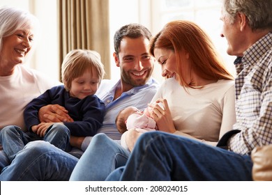 Multi Generation Family Sitting On Sofa With Newborn Baby