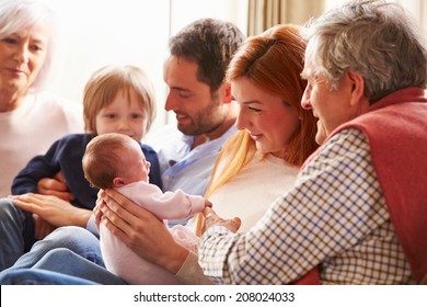 Multi Generation Family Sitting On Sofa With Newborn Baby