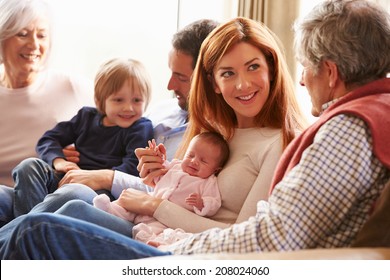 Multi Generation Family Sitting On Sofa With Newborn Baby