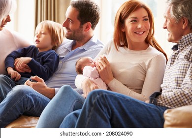 Multi Generation Family Sitting On Sofa With Newborn Baby