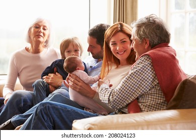 Multi Generation Family Sitting On Sofa With Newborn Baby