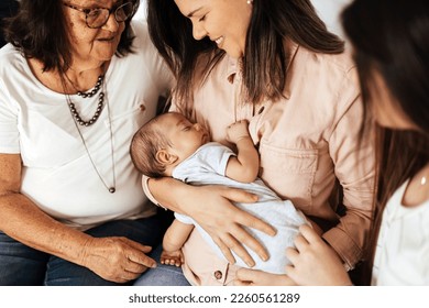 Multi Generation Family Sitting On Sofa With Newborn Baby - Powered by Shutterstock