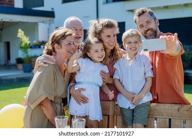 Multi Generation Family Taking Selfie On Backyard In Summer During Garden Party