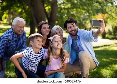 Multi Generation Family Taking A Selfie On Mobile Phone In Park