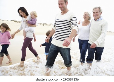 Multi Generation Family Walking Along Beach Together