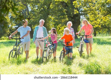 Multi generation family walking in a treelined field with their mountain bikes. - Powered by Shutterstock