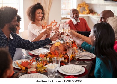 Multi Generation Mixed Race Family Raise Their Glasses To Make A Toast At Their Thanksgiving Dinner Table