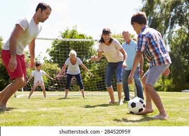 Multi Generation Playing Football In Garden Together
