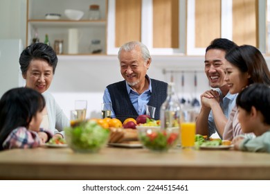 multi generational asian family chatting while having meal together at home - Powered by Shutterstock