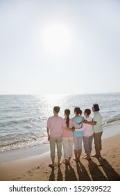 Multi Generational Family, Arms Around Each Other By The Beach, Rear View