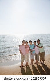 Multi Generational Family Portrait, Arms Around Each Other By The Beach